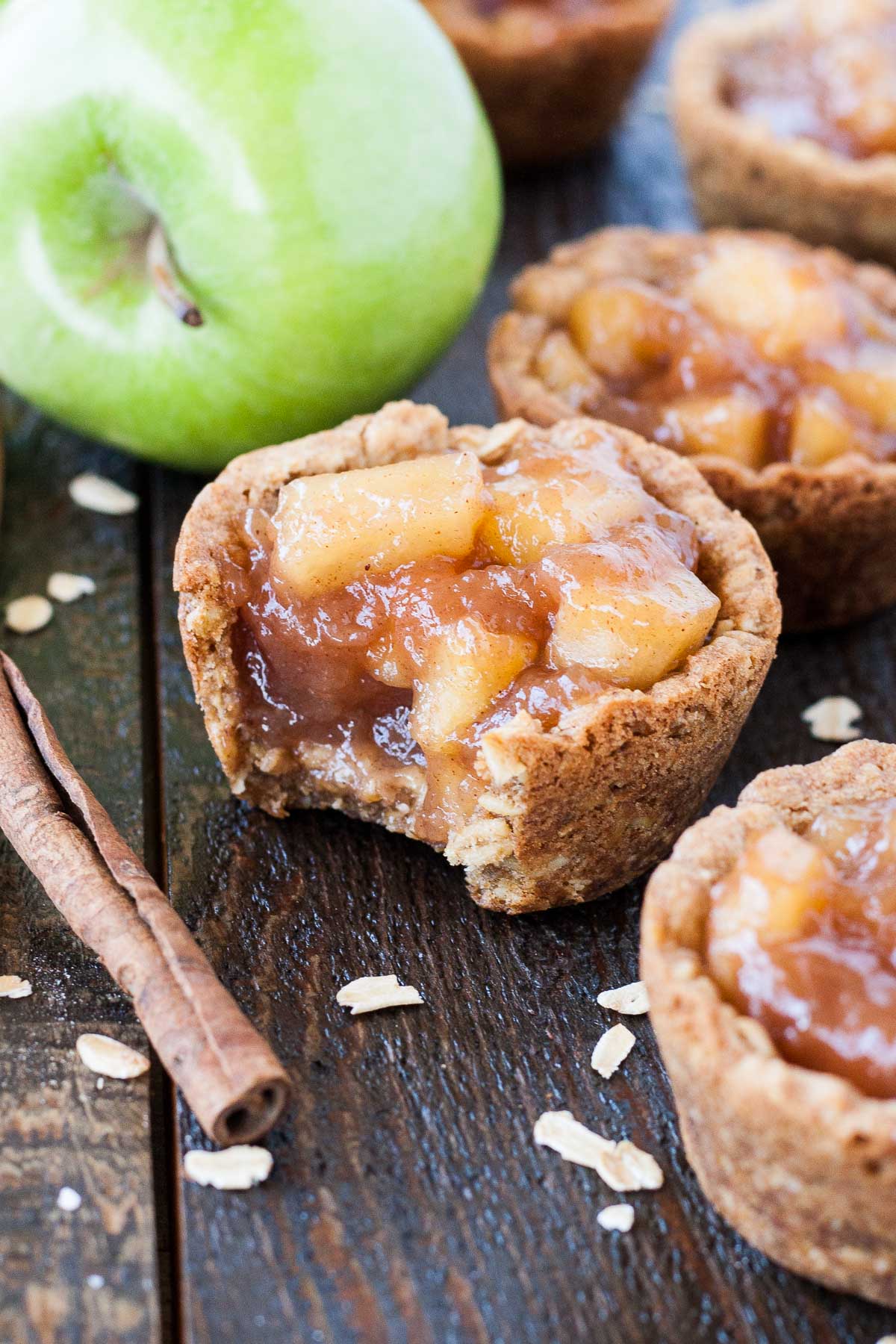 These Apple Crisp Cookie Cups combine classic oatmeal cookies with homemade apple pie filling for the perfect comfort food. | livforcake.com Cookie cup with a bite taken out of it.