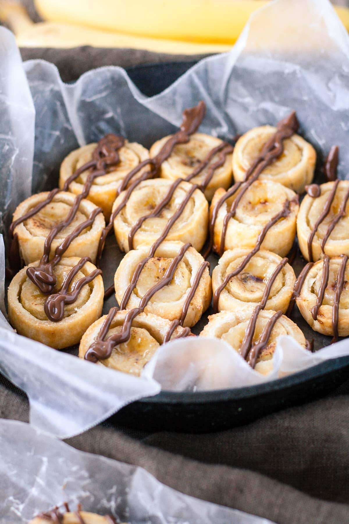 Banana bites drizzled with chocolate on a piece of parchment.