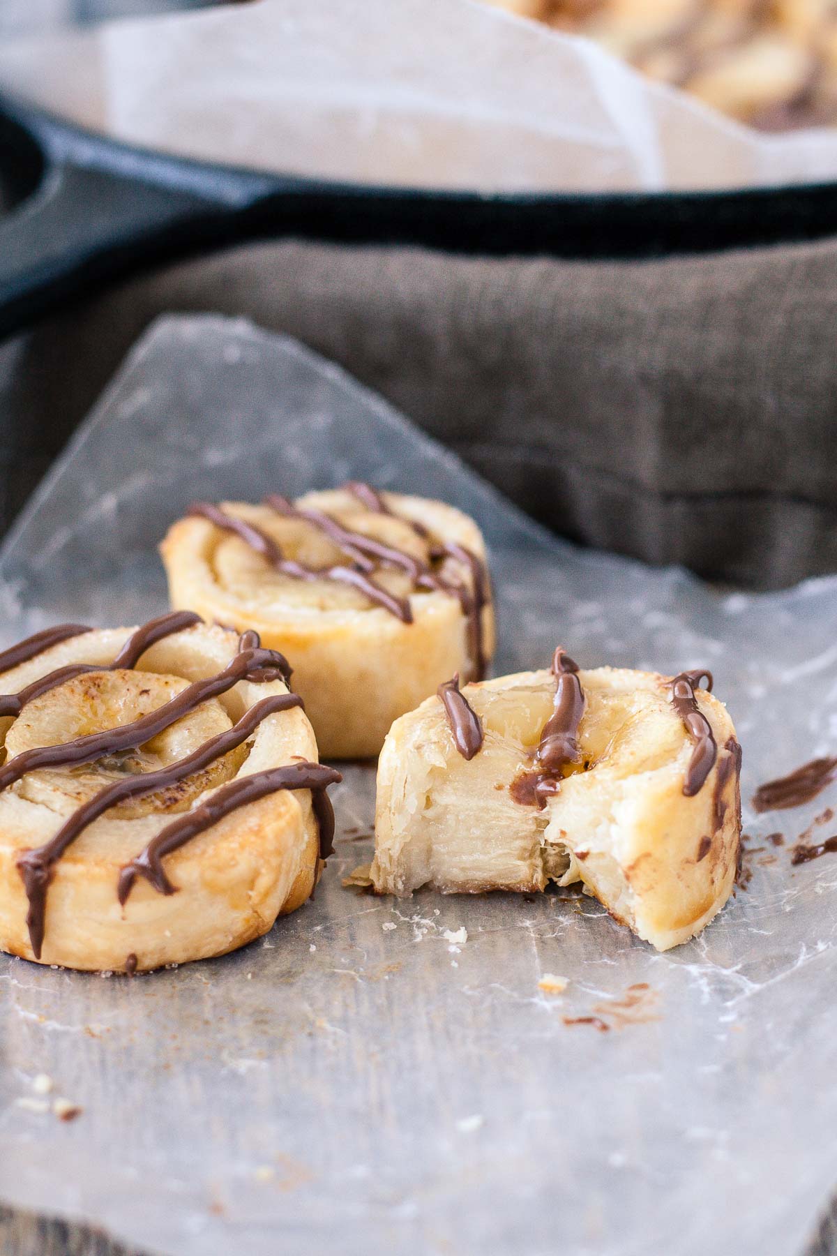 Banana bites drizzled with chocolate on a piece of parchment.