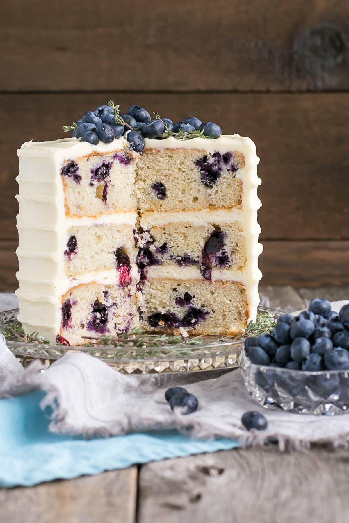 Blueberry Banana Cake! The delicious combination of bananas and blueberries gets paired with a tangy cream cheese frosting in this Blueberry Banana Cake recipe. | livforcake.com Blueberry Banana Cake with Cream Cheese Frosting with slices cut out.