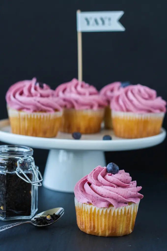 Cupcake in the foreground with cupcakes on a cake stand in the background.