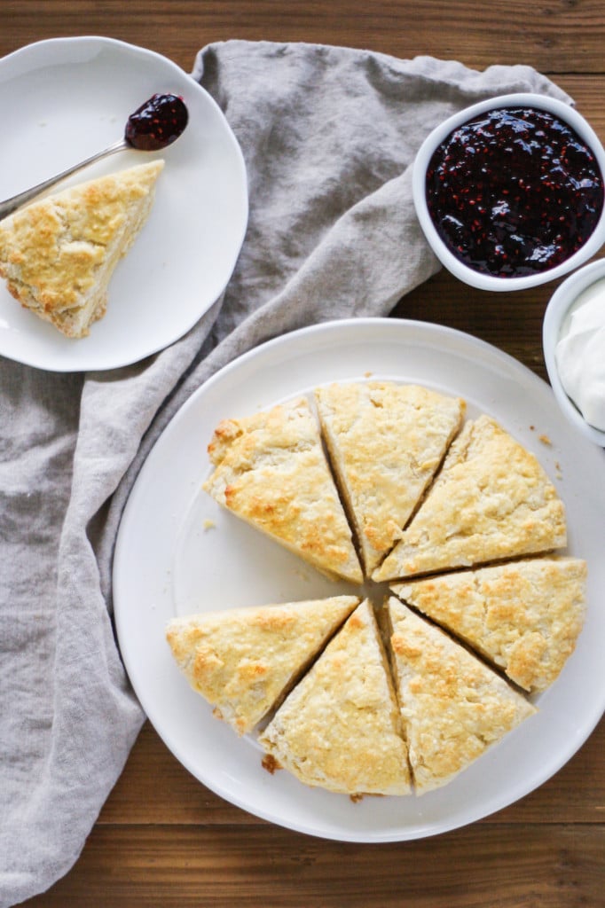 Overhead shot of scones on a plate with a side of jam and cream.