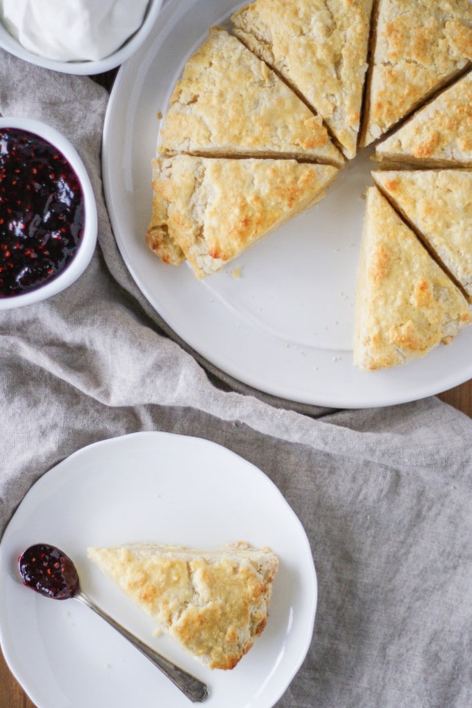 Overhead shot of scones on a plate with a side of jam and cream.