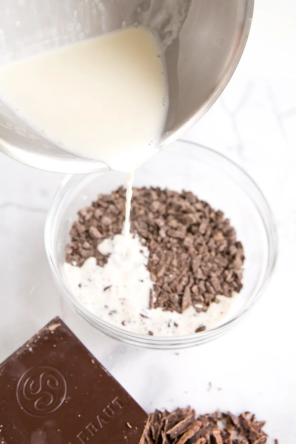 How to make Chocolate Ganache! A simple, two-ingredient recipe for a delicious frosting, filling, drip, or glaze. | livforcake.com Pouring the heated cream from the pot into the bowl of chocolate.