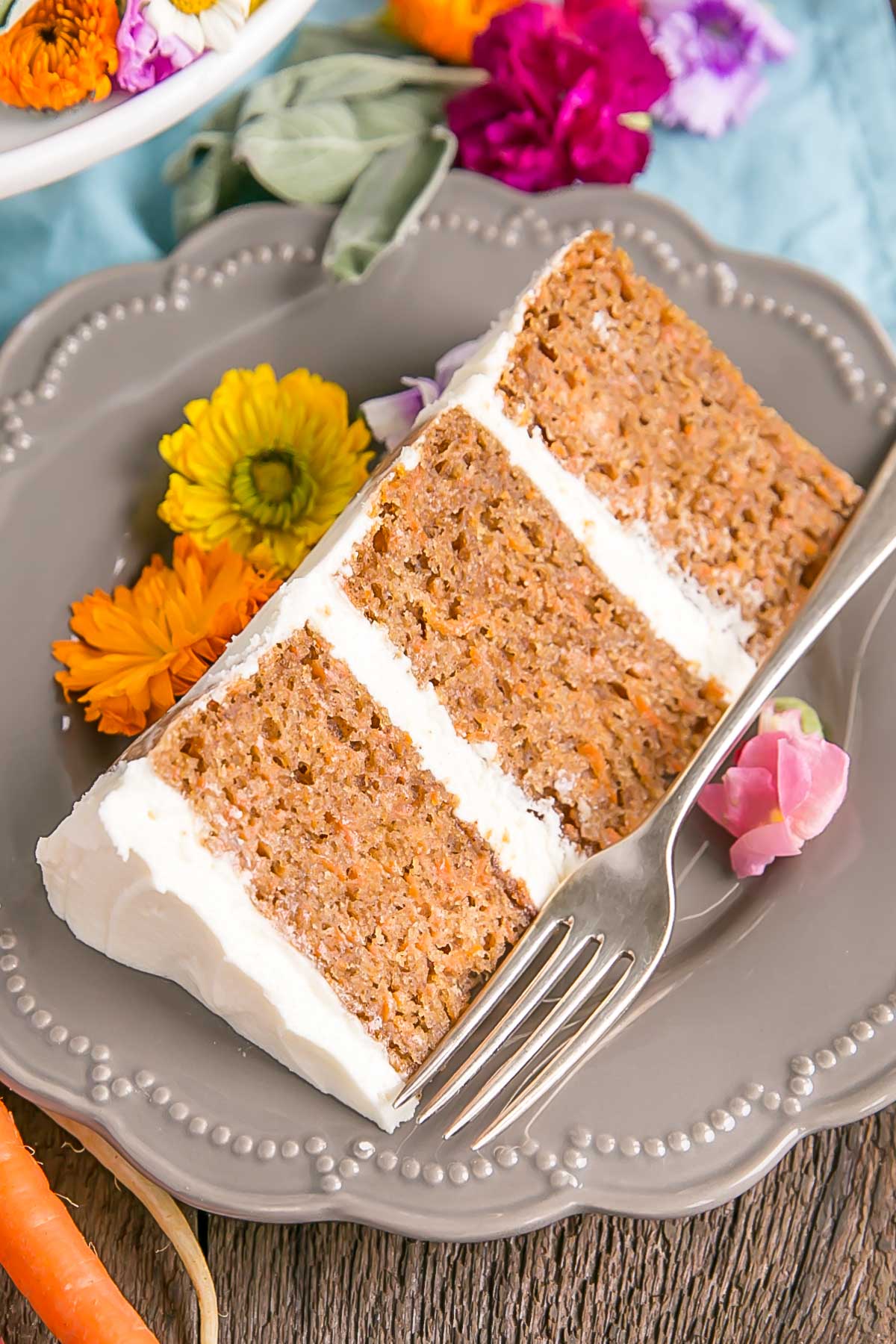 This classic Carrot Cake recipe is one you'll want to add to your collection! A moist and delicious cake paired with a not-too-sweet cream cheese frosting. | livforcake.com Cut slice of a carrot cake with cream cheese frosting.