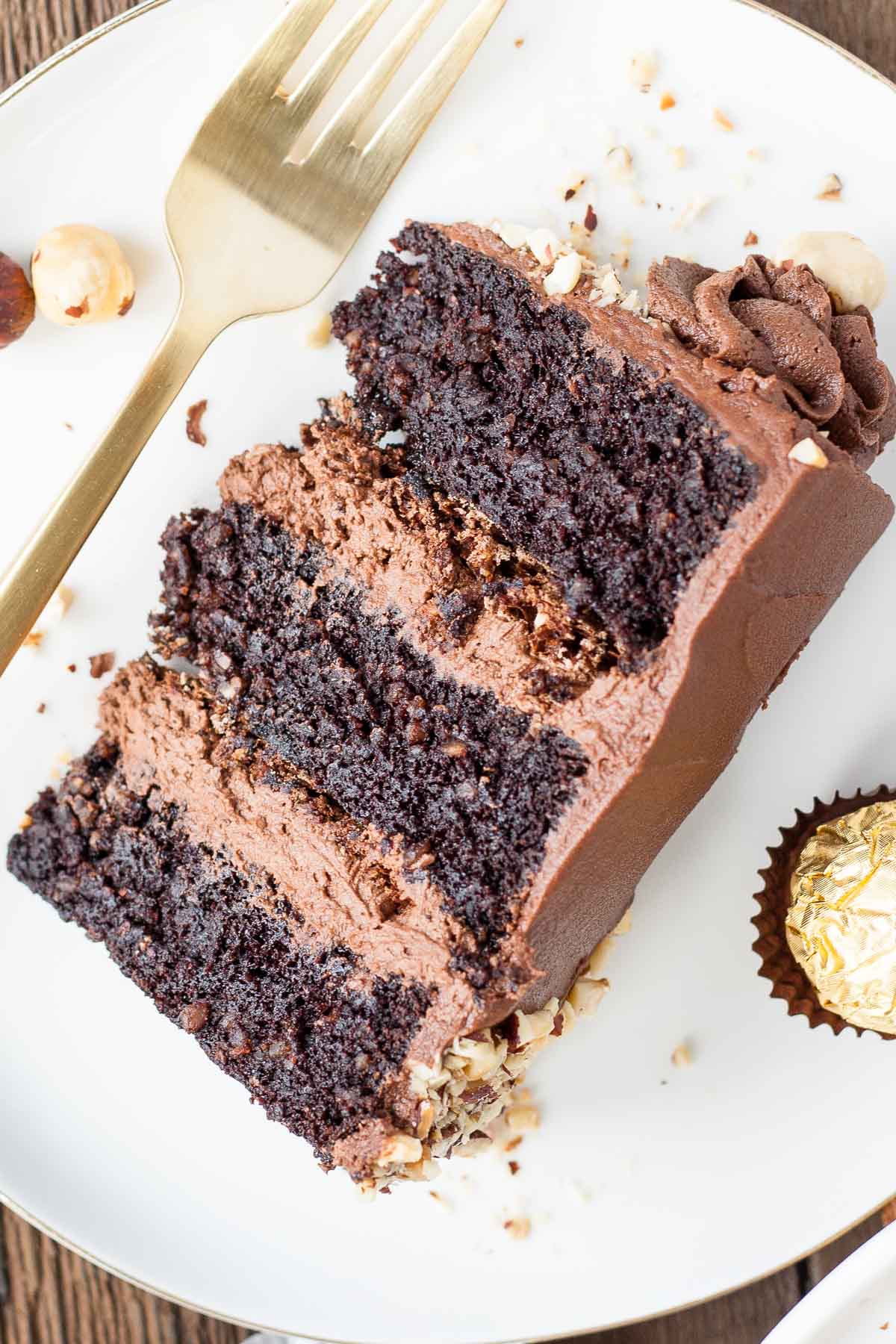 This Ferrero Rocher Cake is your favourite chocolate hazelnut treat in cake form! Chocolate hazelnut cake layers and with a Nutella buttercream. | livforcake.com Slice of cake on a plate.