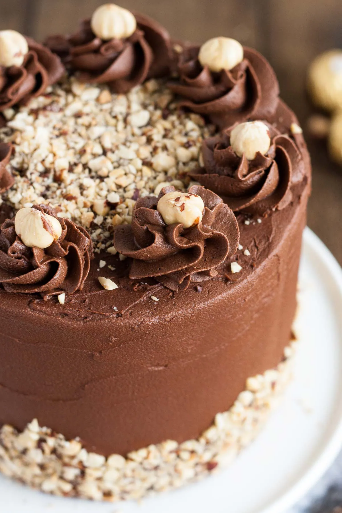 This Ferrero Rocher Cake is your favourite chocolate hazelnut treat in cake form! Chocolate hazelnut cake layers and with a Nutella buttercream. | livforcake.com Close up of a hazelnut topped rosette.