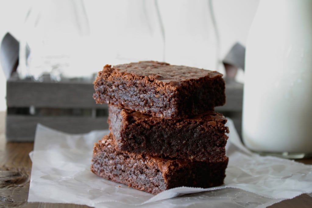 Stack of brownies with a glass of milk.
