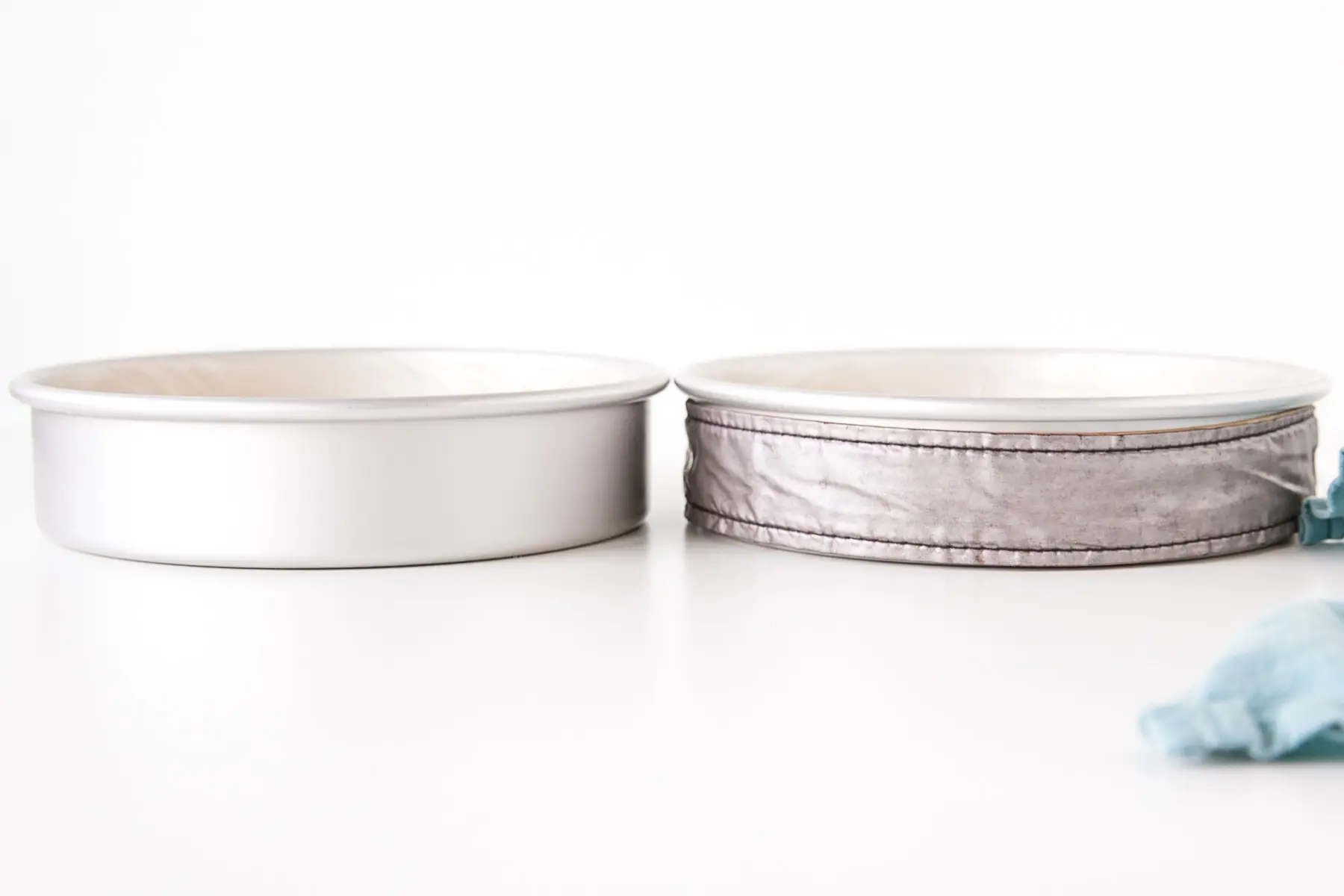 Learn how to bake flat cakes every single time! A simple tutorial on how to make sure your cakes come out nice and flat straight out of the oven. | livforcake.com Two cake pans side-by-side, one with a cake strip around it.