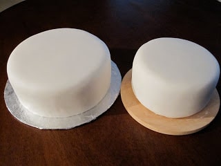 Two cakes side by side covered in white fondant.