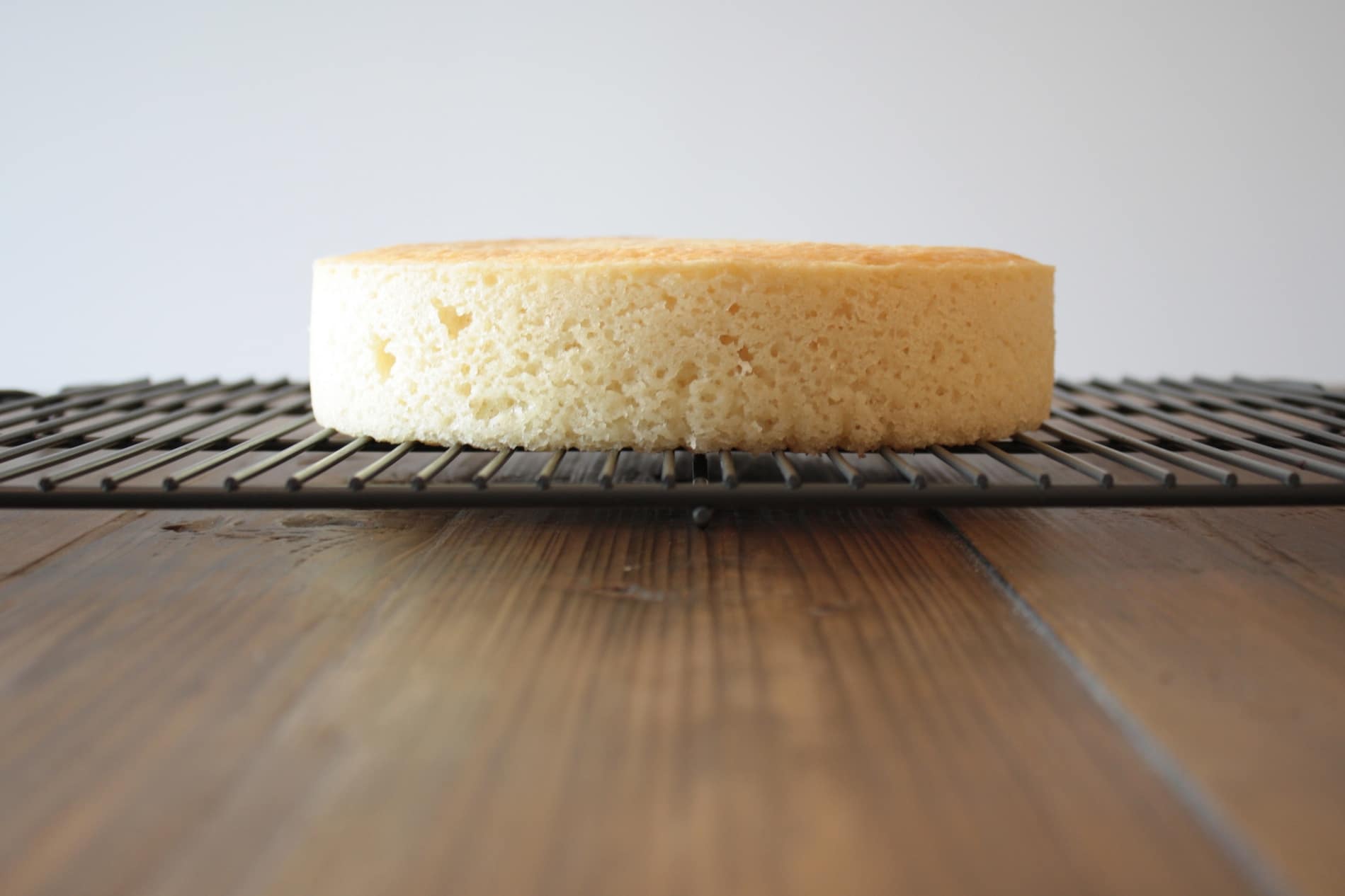 Flat baked cake sitting on a cooling rack.