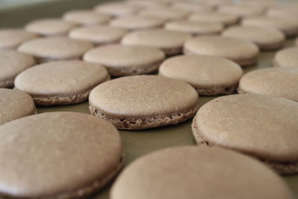 Close up of macarons shells on a baking sheet.