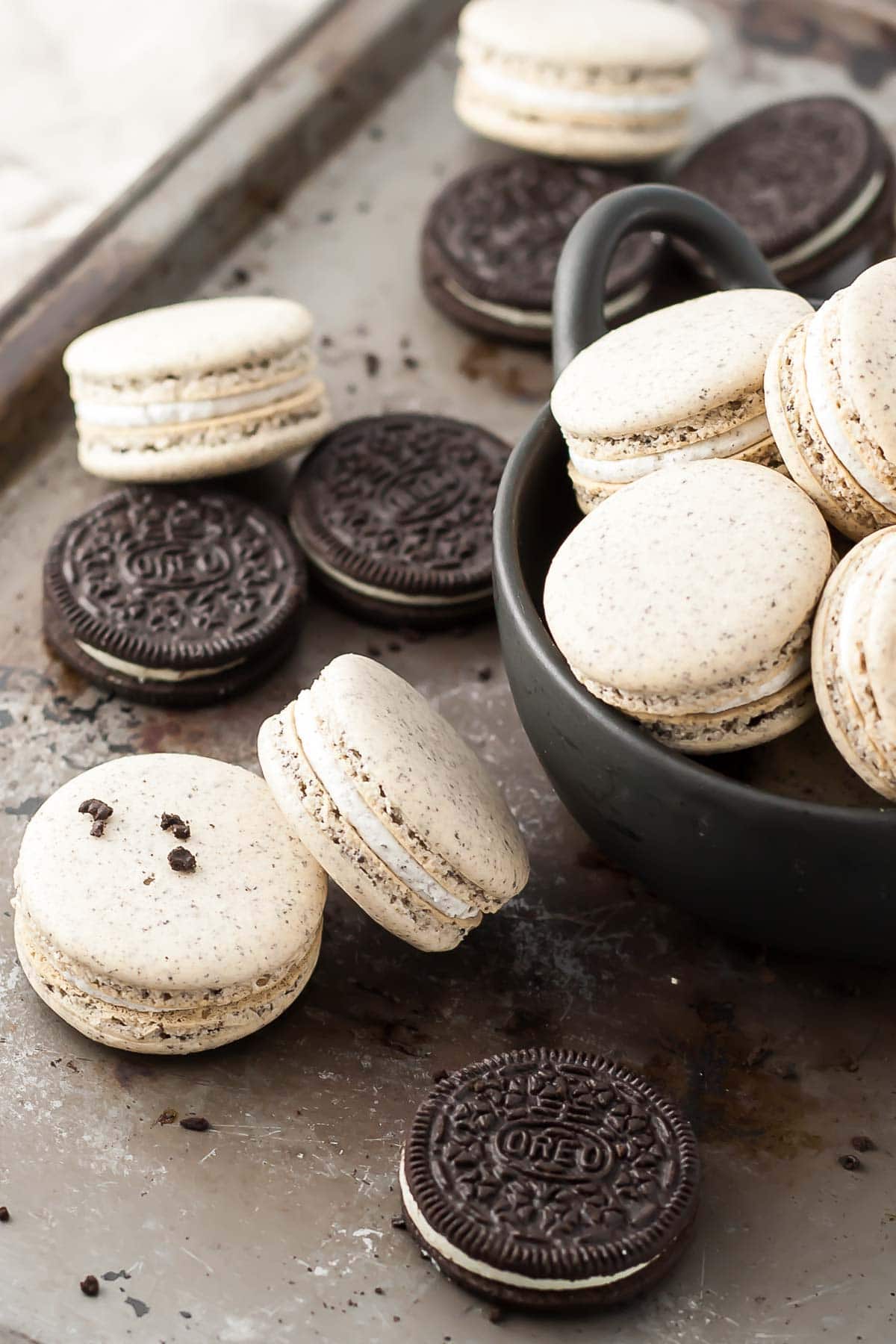 Oreo Macarons! Turn your favourite store-bought classics into something more decadent with these delicate Oreo macarons. | livforcake.com Oreo macarons and Oreo cookies on a baking sheet.