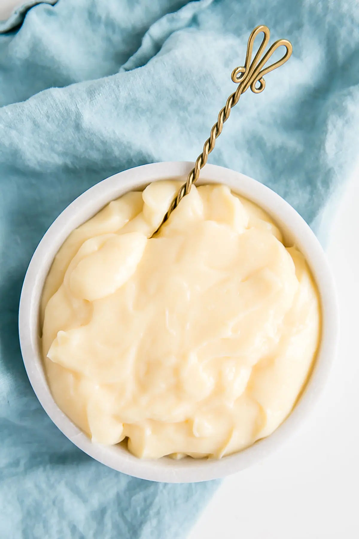 This easy Pastry Cream (Creme Patissiere) recipe is simple and delicious. A rich and creamy vanilla custard you can use in a variety of decadent desserts. | livforcake.com A spoon in a bowl of Creme Patissiere.