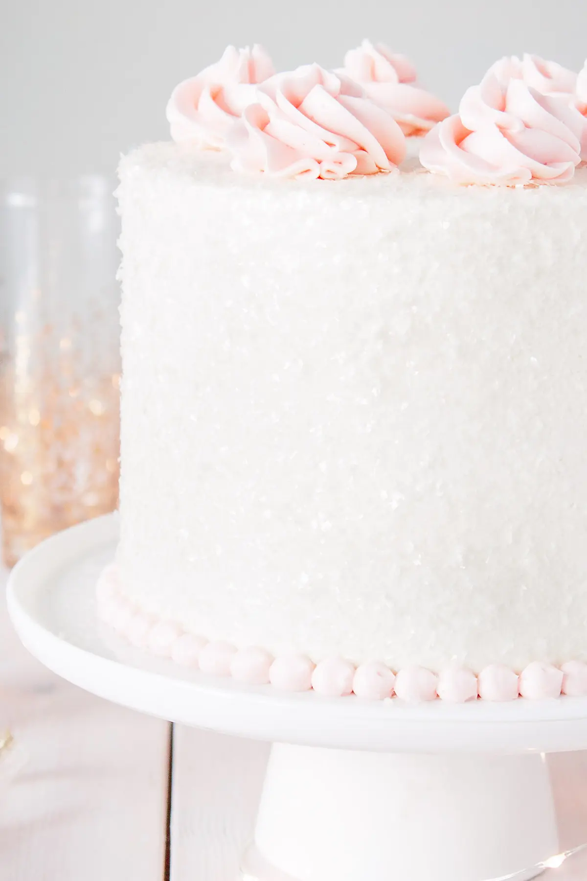 This Pink Champagne Cake is the perfect way to celebrate any occasion or holiday! A champagne infused cake with a classic vanilla buttercream. | livforcake.com Close up of cake sparkles on a pink champagne cake.