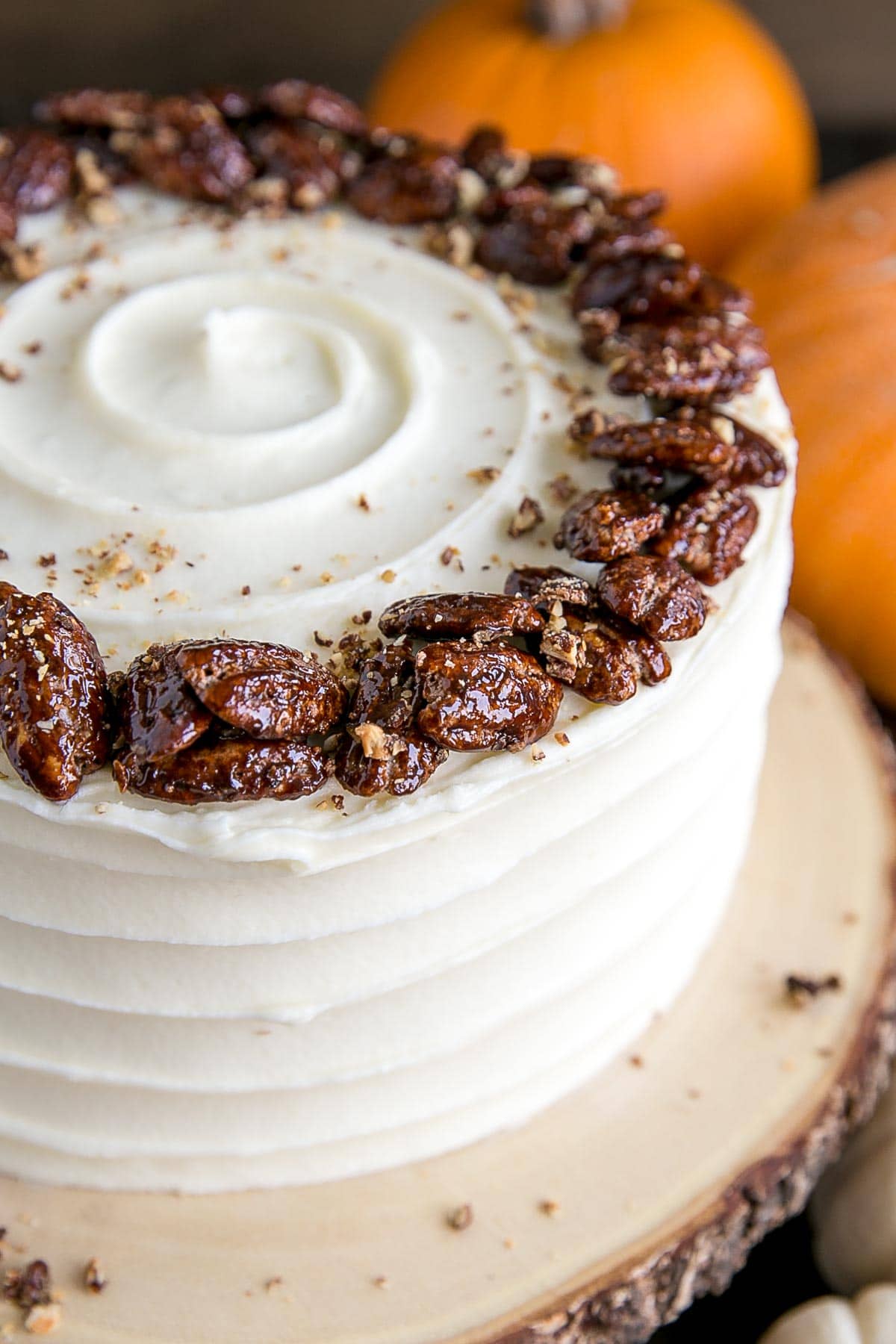 This pumpkin cake is perfect for Fall! Moist and delicious pumpkin cake layers with a tangy cream cheese frosting and crunchy candied pecans. | livforcake.com Close up of the pecans on top of the cake.