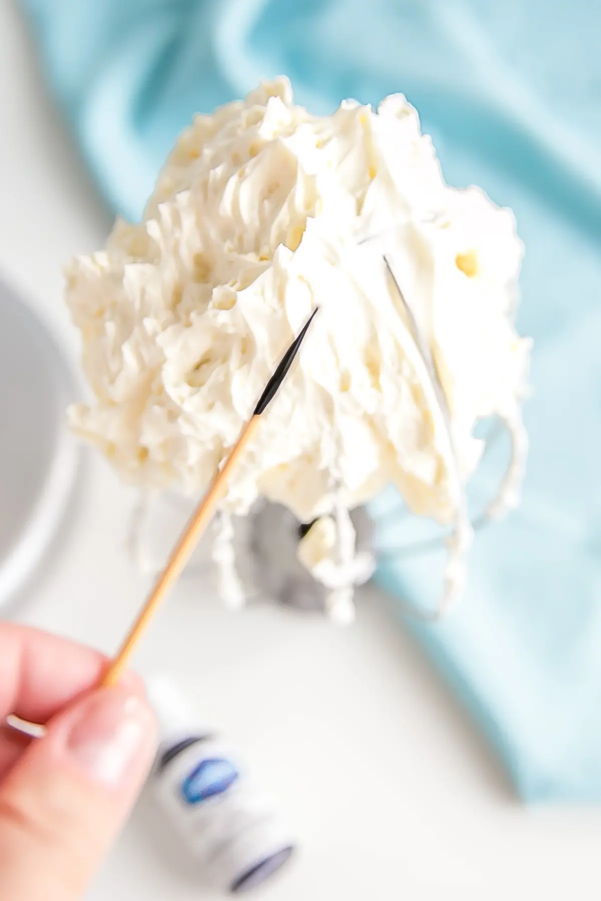 This tutorial on how to make Swiss Meringue buttercream is the only resource you'll need to make the smoothest, silkiest frosting! | livforcake.com Toothpick with violet color gel to help make the buttercream white.