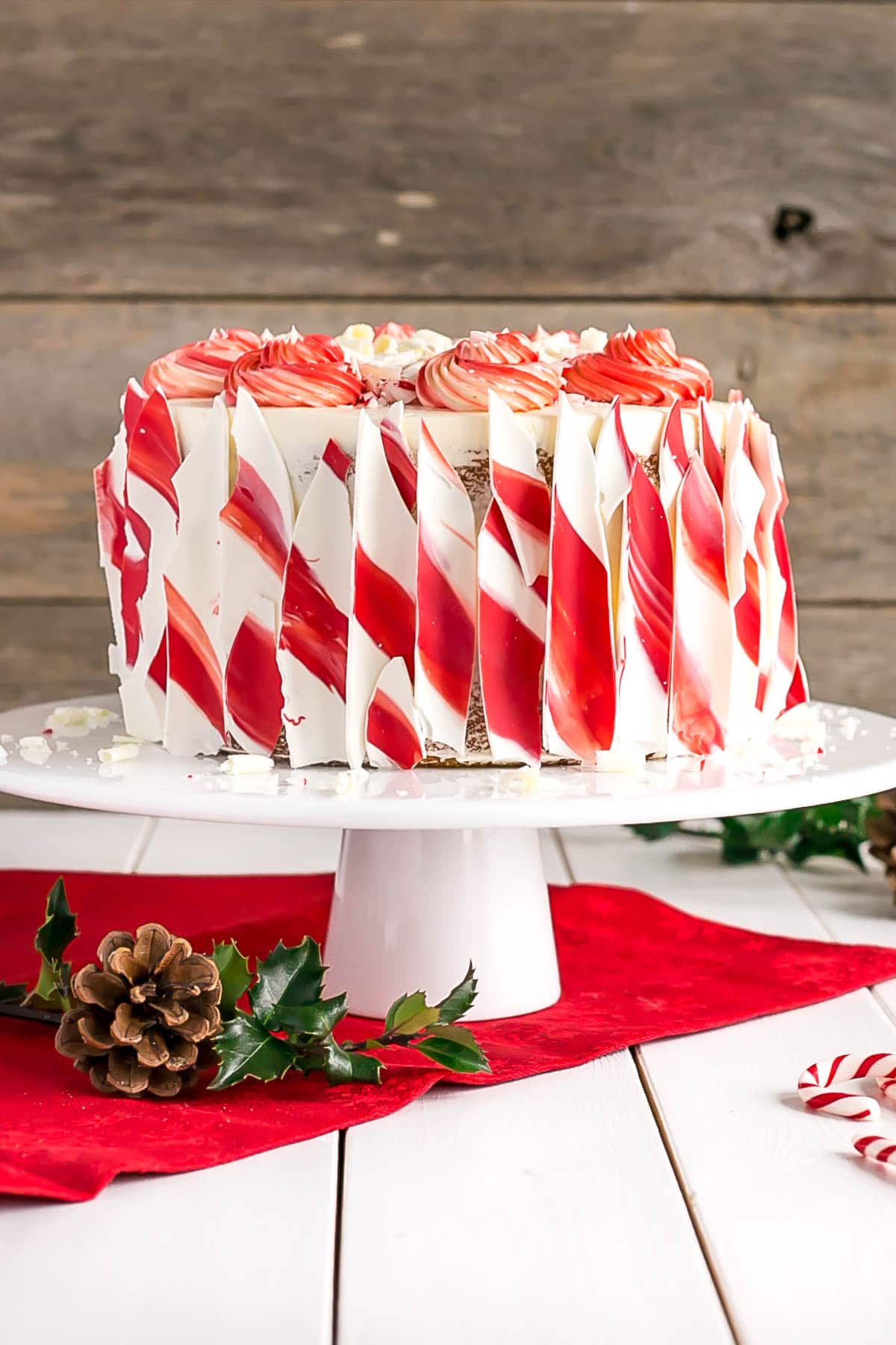 This White Chocolate Candy Cane Cake is the perfect addition to your holiday celebrations! | livforcake.com White Chocolate Candy Cane Cake on a white cake stand